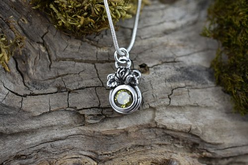 A delicate symbol of timeless beauty, this small sterling silver pendant features a 6mm olive green cubic zirconia, under a f...