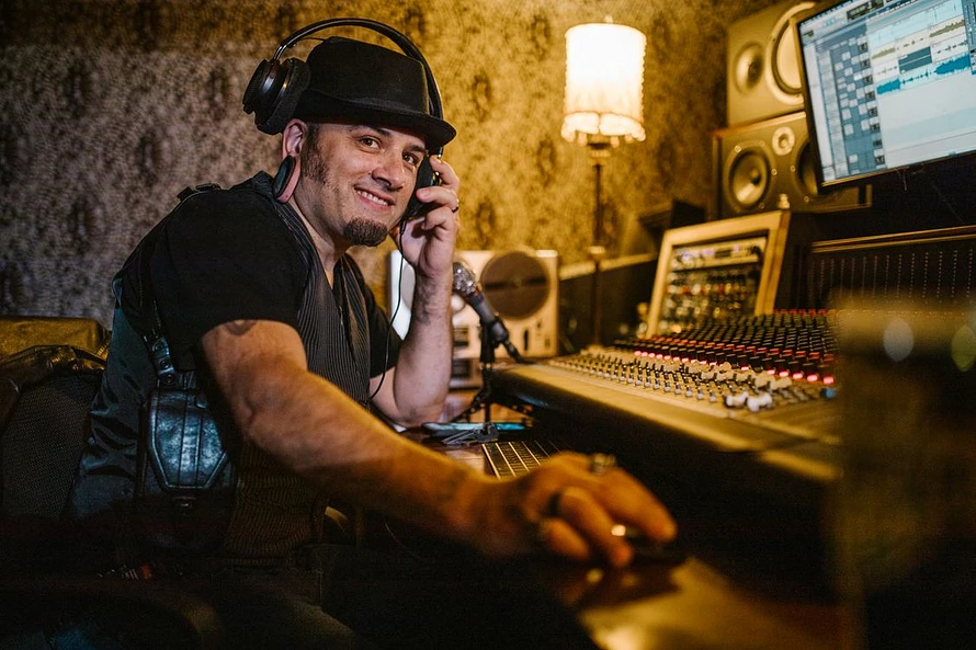 Smiling music producer wearing headphones at a professional audio mixer in a recording studio