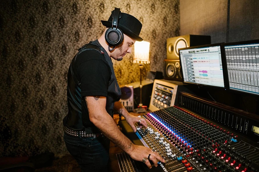 Music producer wearing headphones with a console in a music recording studio 