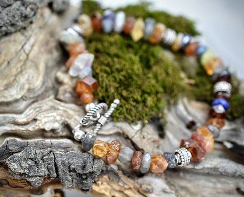 This exquisite bracelet showcases a harmonious mix of stones, with warm hessonite garnet taking center stage, beautifully com...
