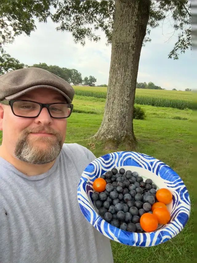 Picked a few blueberries and tomatoes today before tonight’s rain rolls in. 🍅🫐 I’ve got a few heat tolerant rabbiteye blueberry bushes here in Middle Tennessee and they’ve done great here. This year’s garden has been a rough one though. We got hit with a late cold spell, flooding, deer, rabbits, and about everything else you can imagine to slow me down. 😂 But I’m still at it. Hoping the okra will be ready before long! Wearing the Peaky Hat Dudley Solo in this heat. #Gardening #GardenLife #Homegrown #GrowYourOwn #VegetableGarden           