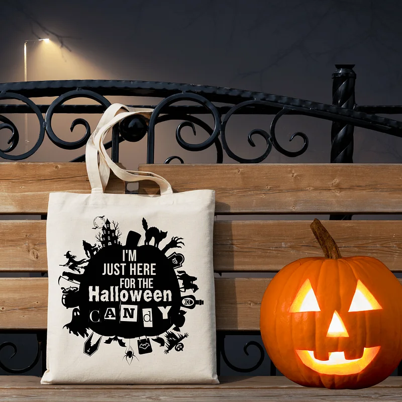 This image is of a canvas tote bag the says "I'm Just Here for The Halloween Candy" with a jack-o'-lantern next to it.
