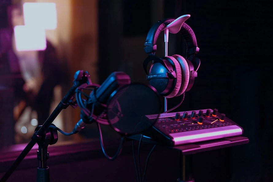Professional audio recording equipment including microphone, headphones, and mixer board in a dim studio