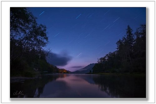 Star trails over Lake Crescent from the mouth of the Lyre River — deep blue sky, pink twilight glow, glassy water reflecting ...