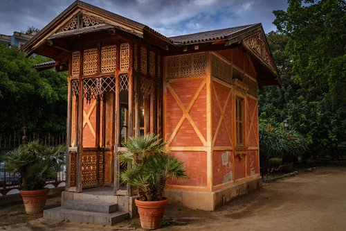 The worn textures and intricate woodwork of this Palermo garden security hut caught my eye immediately. That striking red ext...