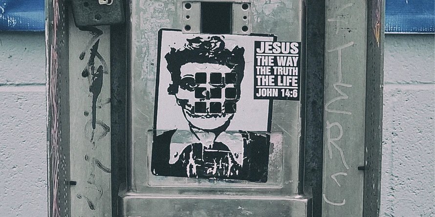 Close-up of a weathered Pacific Bell payphone covered with a Lucille Ball and Misfits skull sticker, a 
