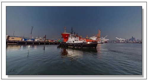 Crowley's Tug Guard working a ship assist in the Port of Seattle — that bold red hull towering over her, downtown skyline and...