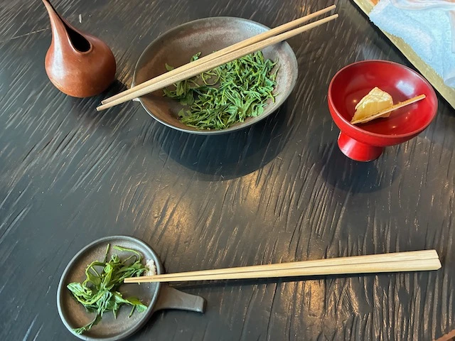 Chopsticks placed over cooked green tea leaves