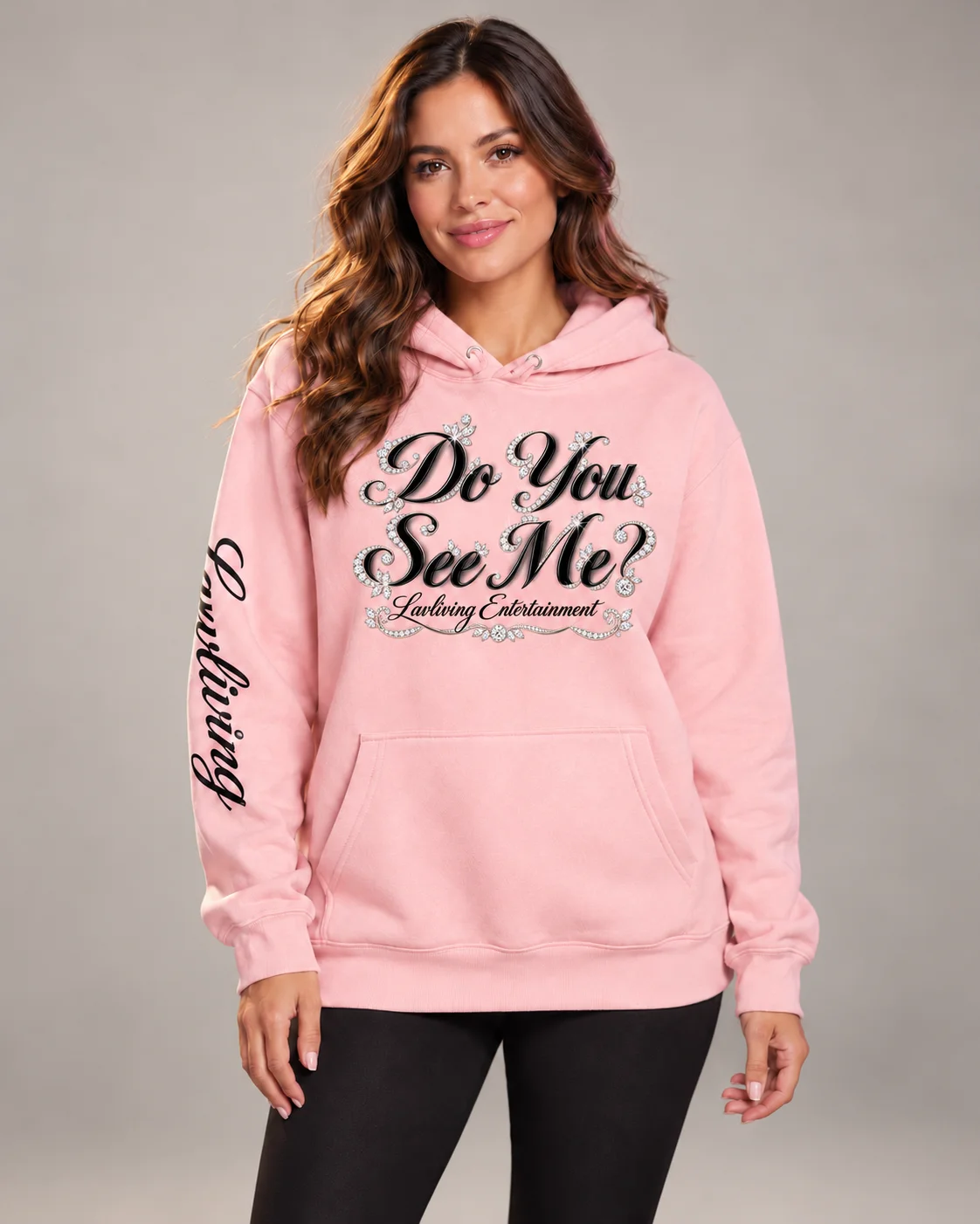 Model wearing a Light Pink Lavliving Do You See Me? special-edition hoodie with black cursive lettering and diamond accents.