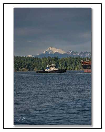 Crowley’s Tug Valor turning a ship around in Guemes Channel — Mt. Baker breaking through the storm clouds overhead, red hull ...
